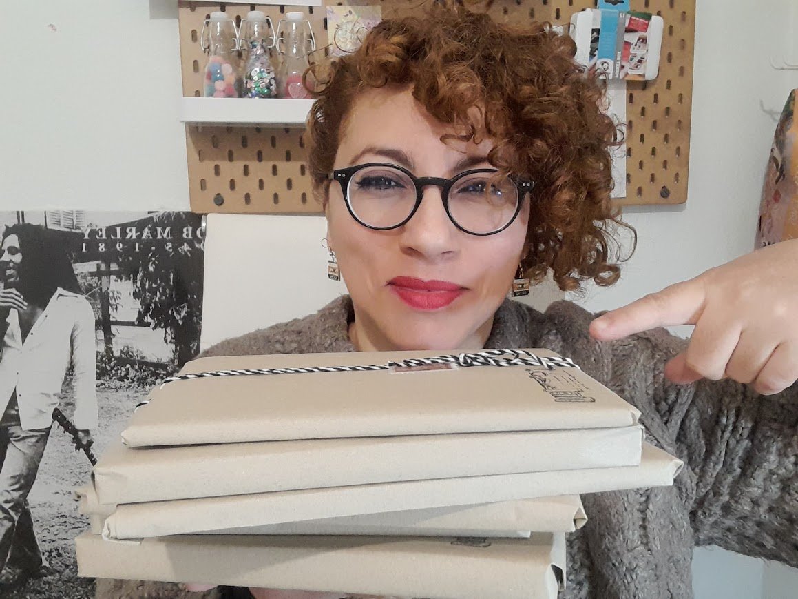 Mujer con gafas sosteniendo varios libros envueltos en papel kraft